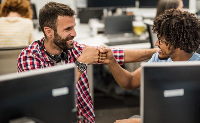 Two men fist bump at a custom logo design company office