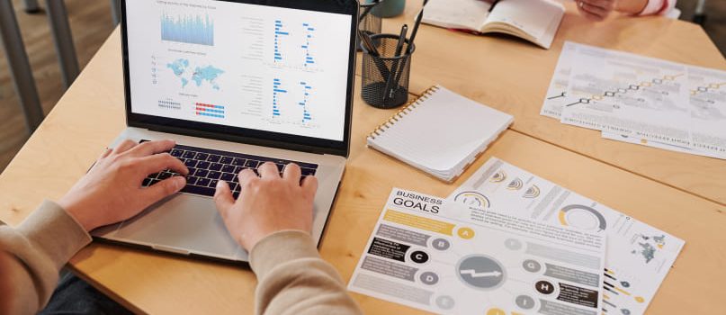 Web designer works on CMS with sheets of paper on their desk