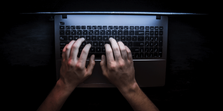 Top-down view of an obscured laptop keyboard to show a cyber criminal compromising Magento store security