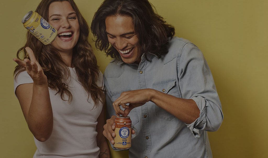 A background image for Buddha Brands of two friends laughing with cans of drink