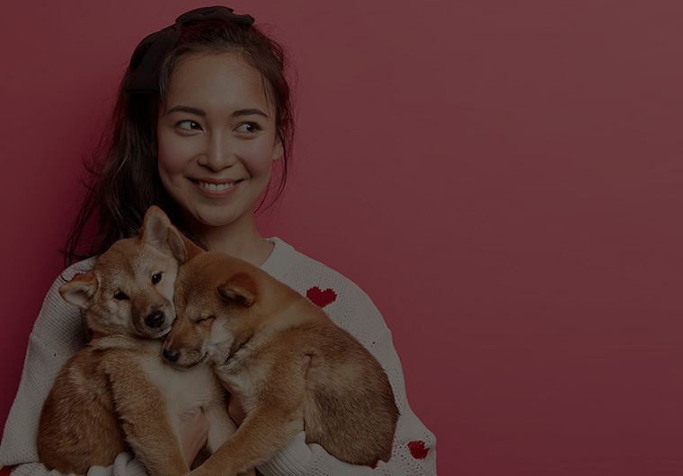 smiling woman holding two puppies