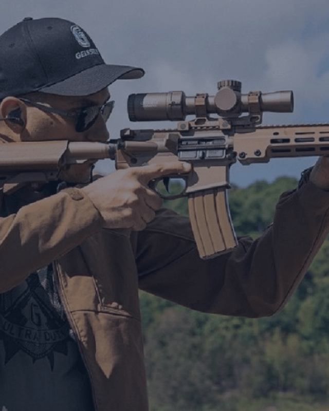 A man looks down the visor of his gun