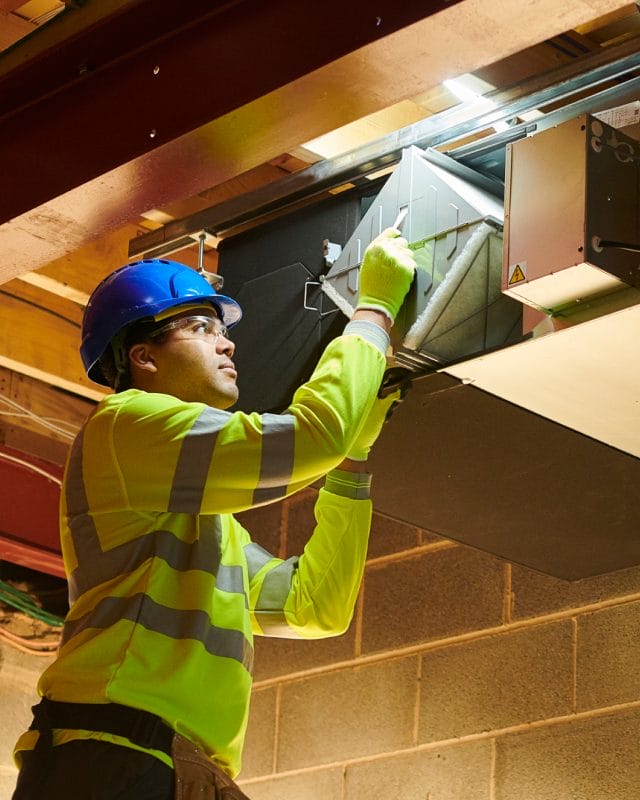 A man in safety gear holds a box