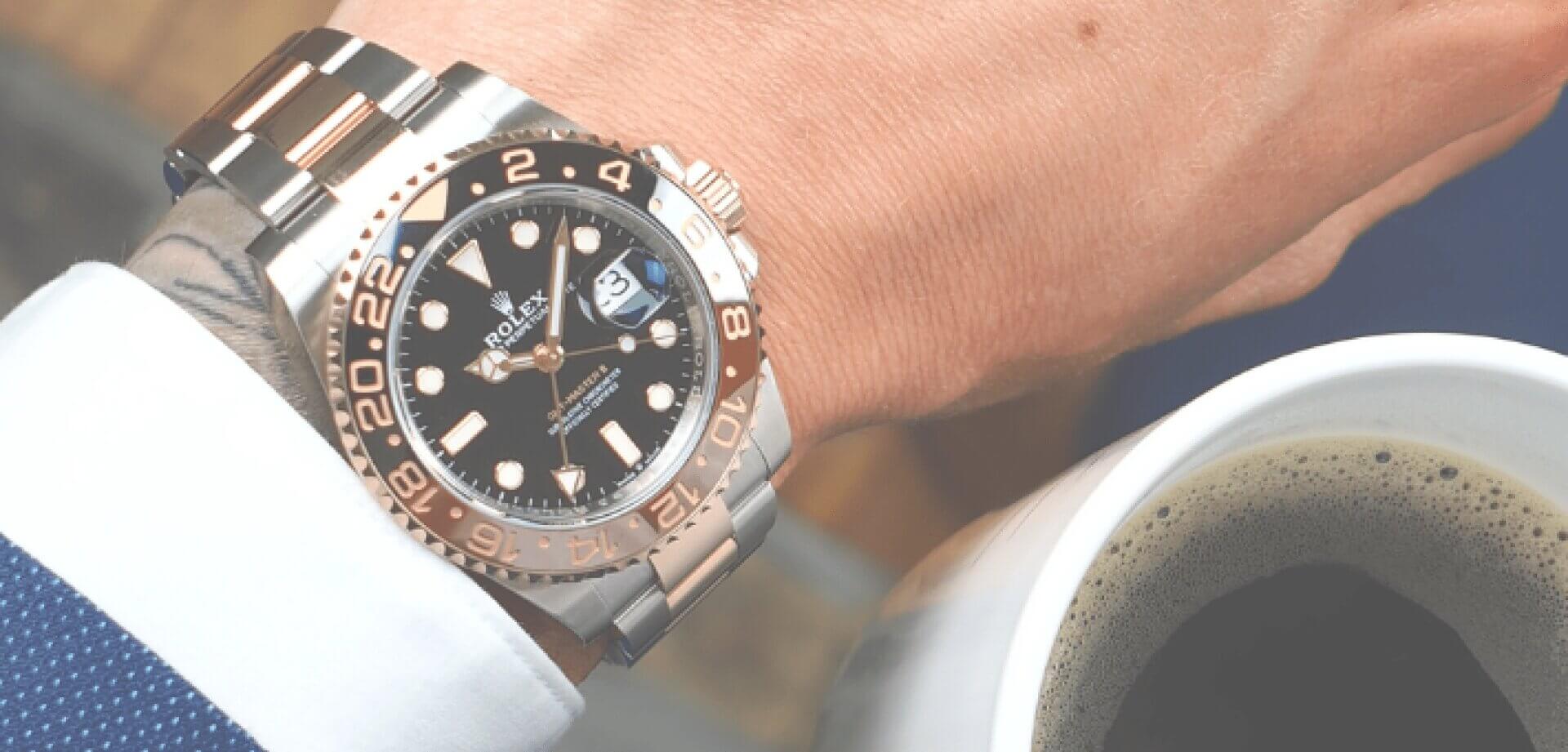 Close-up of a luxury Rolex wristwatch on a person's wrist beside a cup of coffee, showcasing premium craftsmanship, elegant design, and timeless style.