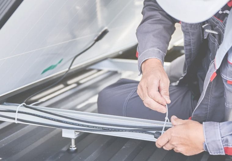 Technician securing cables with a zip tie during installation.