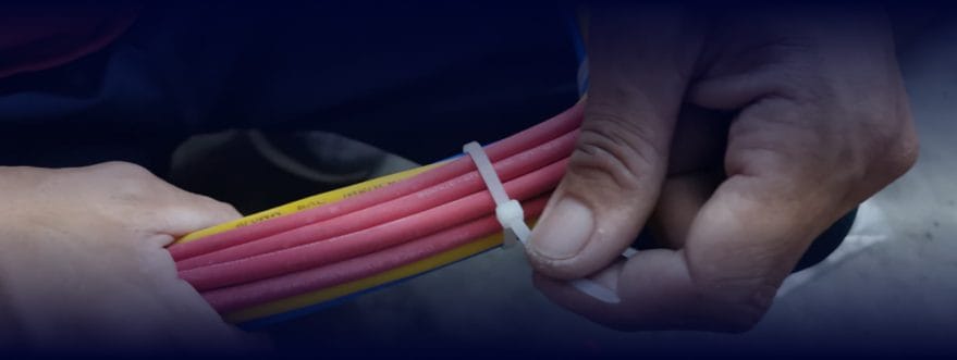 Close-up of hands tightening a zip tie around bundled wires