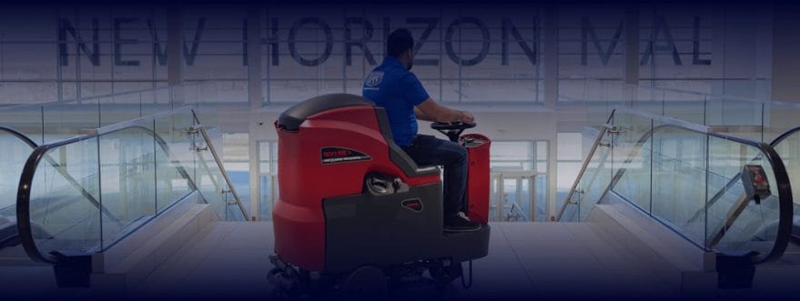 picture-perfect-cleaning-background-2 Cleaner driving a ride-on floor scrubber between escalators