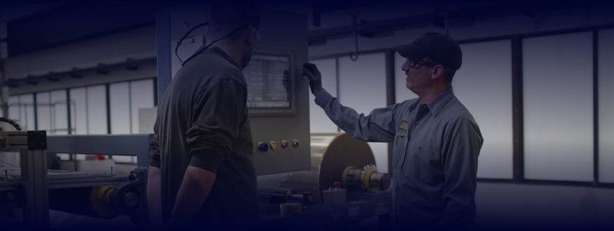 boston-materials-backgorund-2 Background image for Boston Materials' case study showing two manufacturing workers operating a control panel on a factory floor