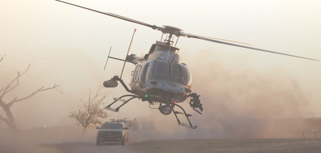 Background image for Helinet Aviation's case study showing a flying helicopter with cars on the road behind it