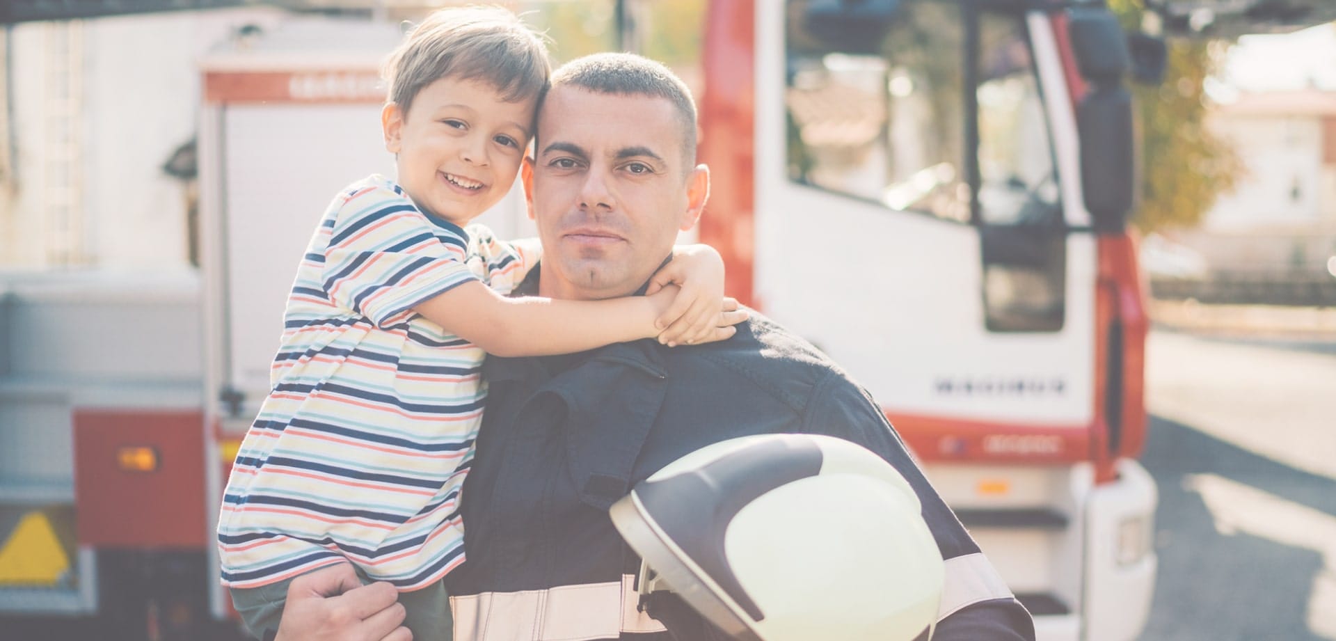 Background image for Project Fire Buddies' case study showing a firefighter with his child in front of a fire truck
