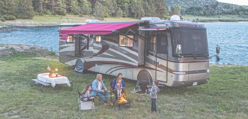 Background image for ShadePro's case study showing a family camping by a lake with their RV and a campfire at dusk