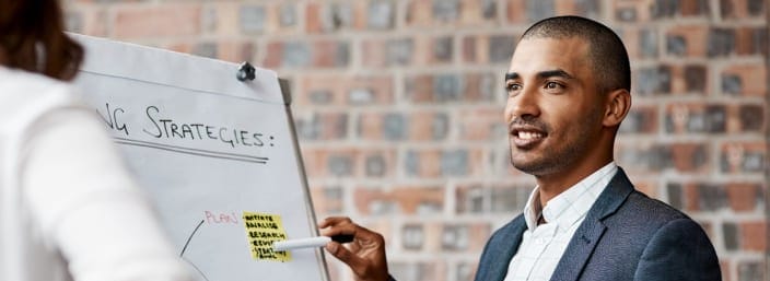 A professional presents ideas on a whiteboard with sticky notes during a meeting