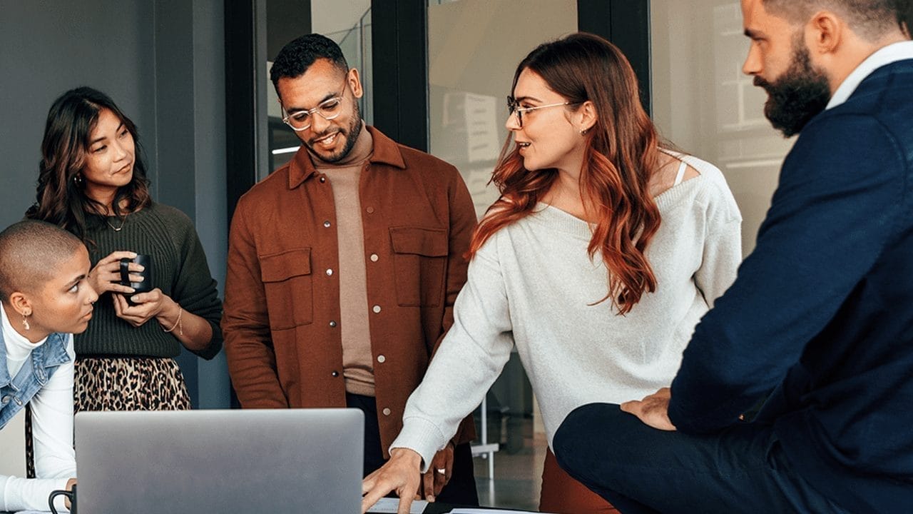 A group of people talking and looking at a computer