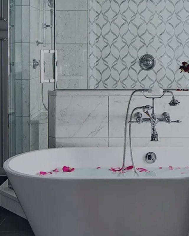 Modern bathroom with a freestanding bathtub, chrome fixtures, tiled walls, and a glass shower, showcasing residential plumbing