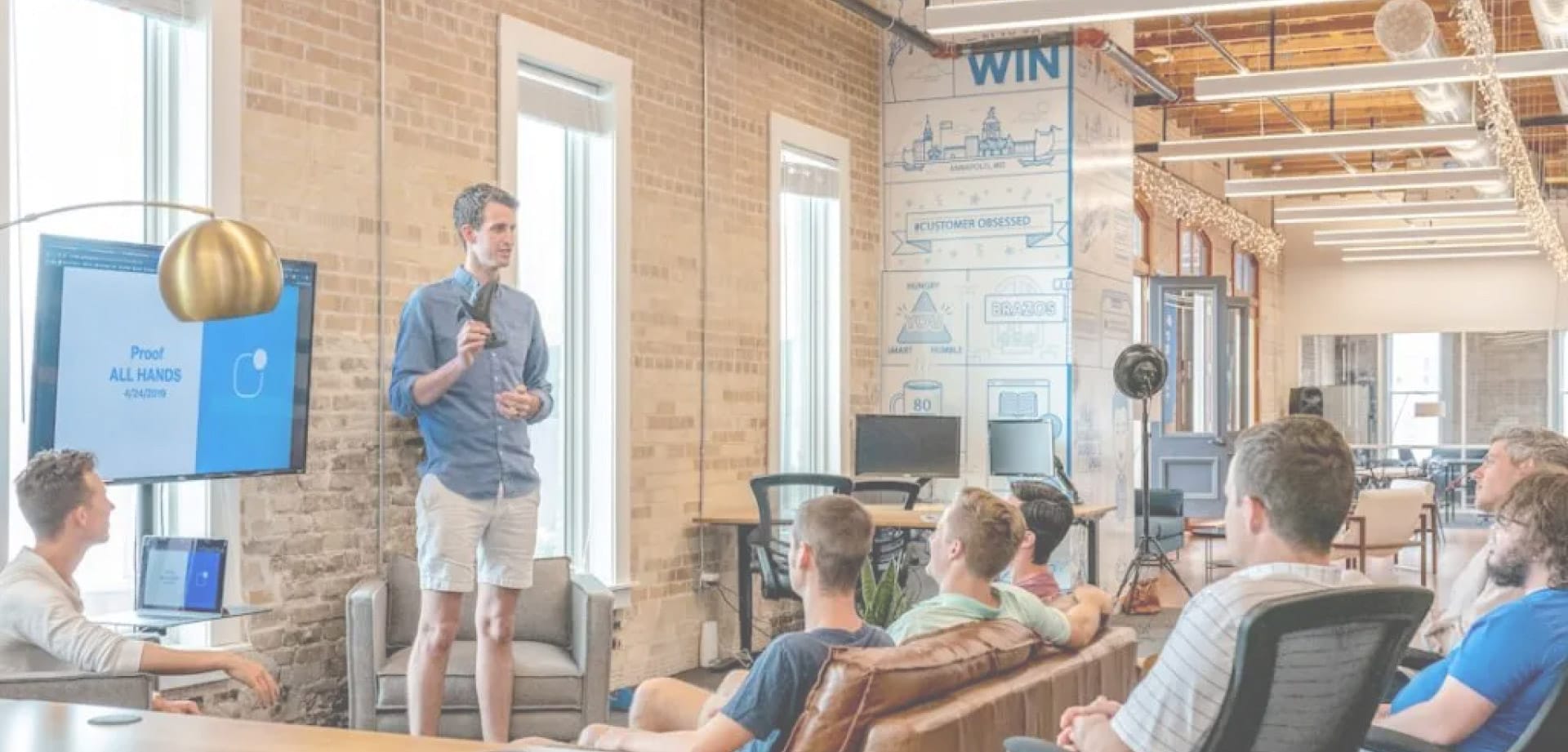 Startup founder presenting to a group in a modern office during a team or investor meeting.
