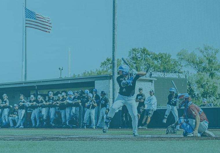 Baseball player batting during a game with teammates in the background