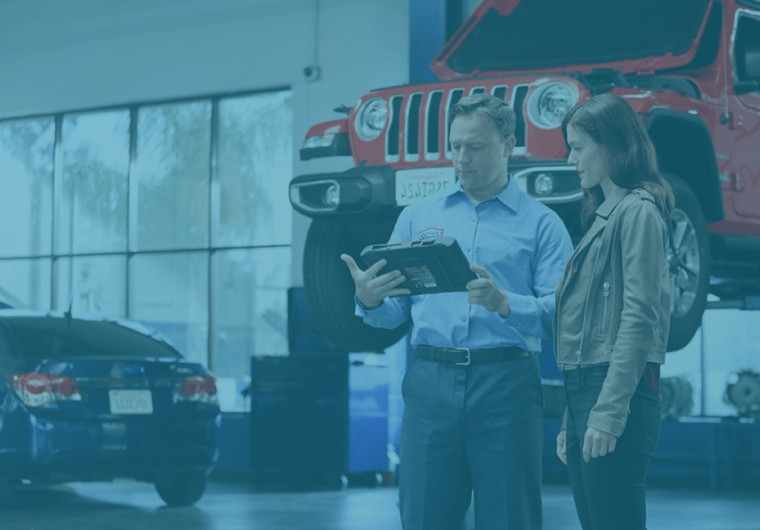 Service advisor showing a tablet to a customer inside an auto repair shop