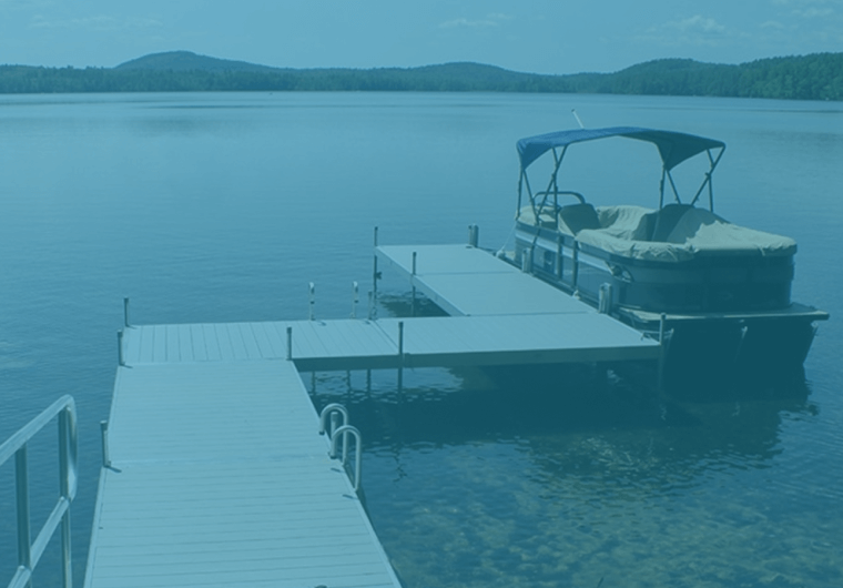 Blue-toned lake view with a dock leading to a covered pontoon boat