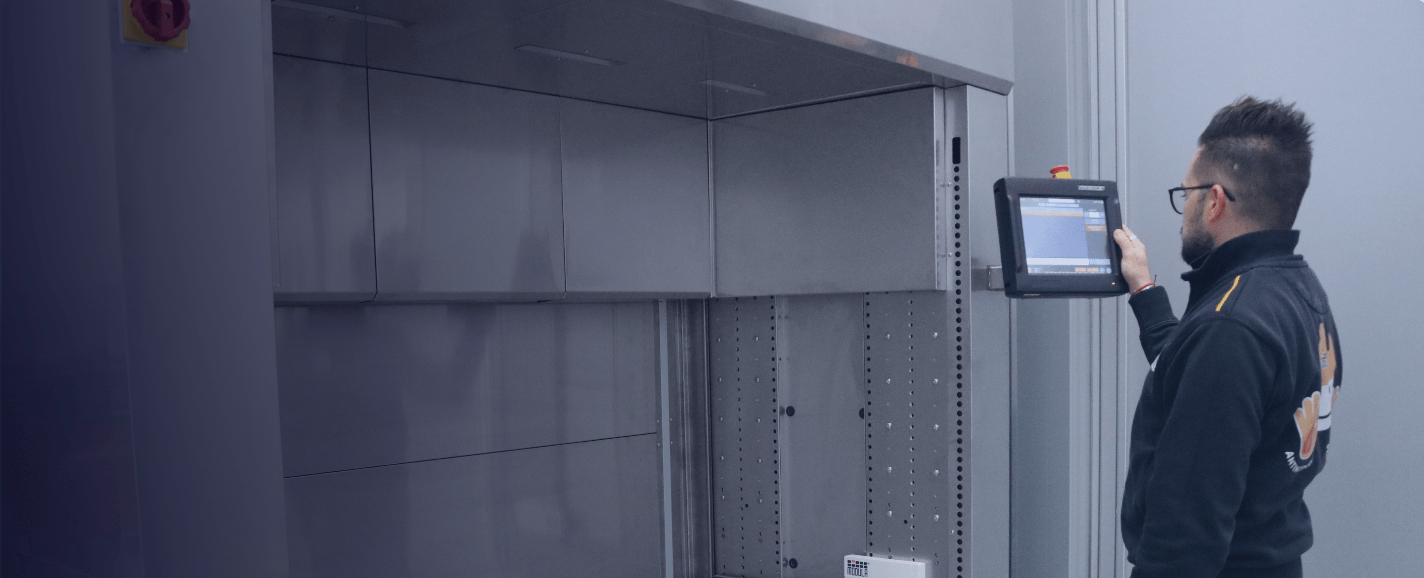 Man using a touchscreen control panel on an automated vertical lift system.