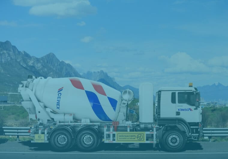 Cemex cement mixer truck driving on a highway with mountains in the background