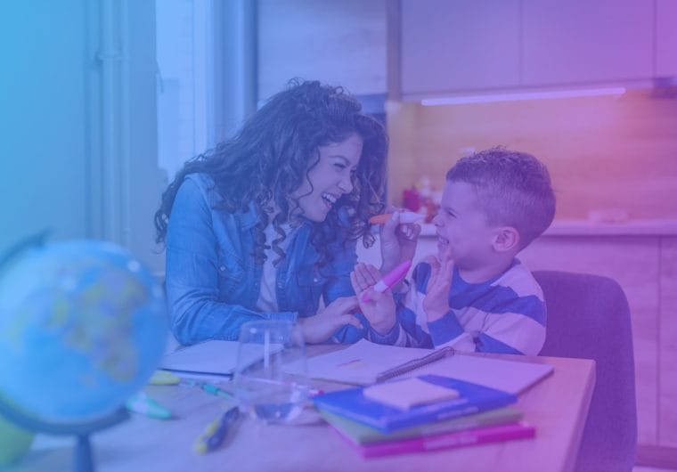 Therapist and young boy laughing together at a desk covered with school supplies, with a blue-to-purple gradient overlay
