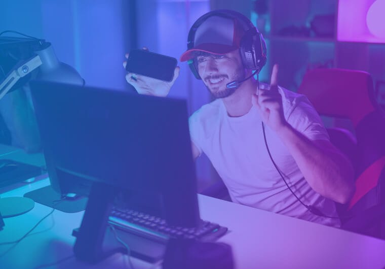 Person wearing a headset and cap sits at a desktop computer
