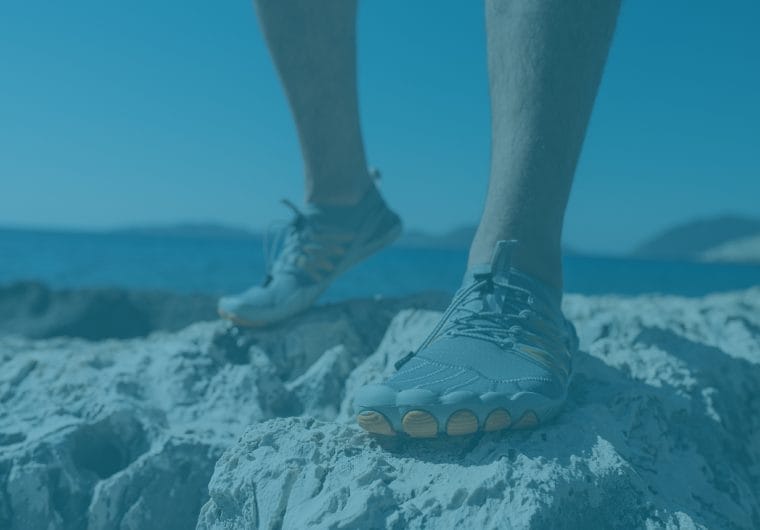 product-website-design-onday-shoes-background Close-up of a person standing on rocky terrain near the water