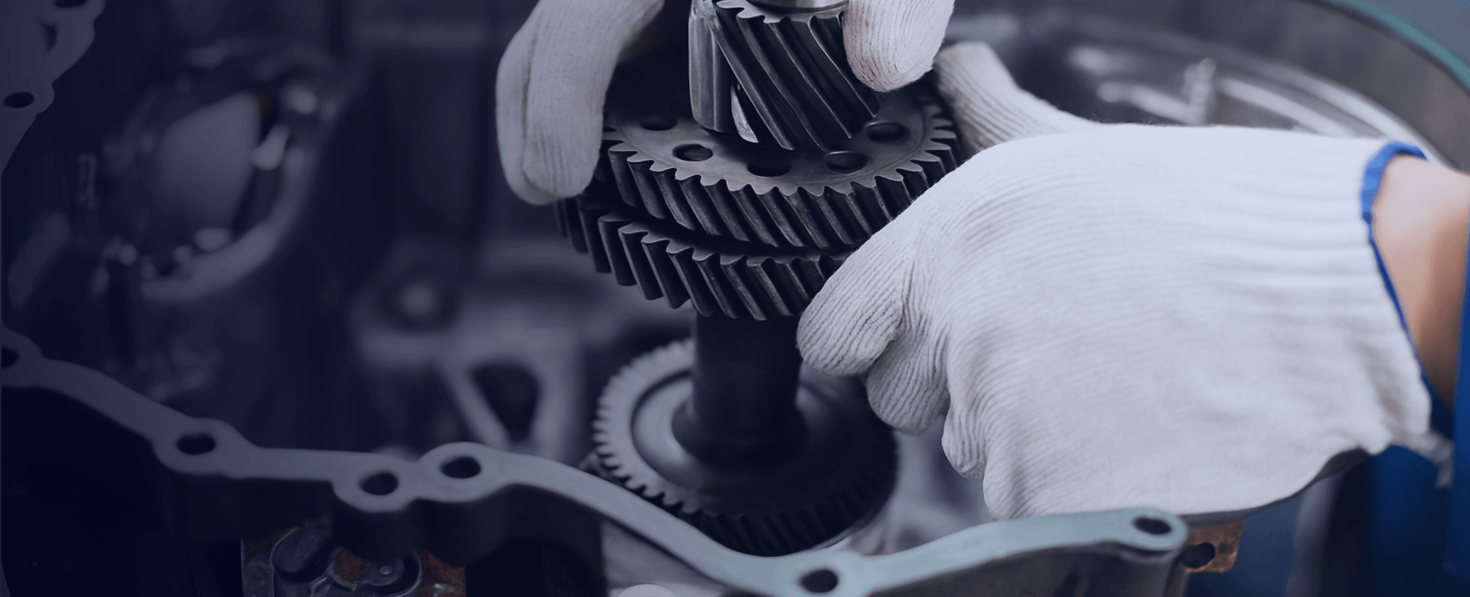 Gloved hands assembling metal gears inside a machine