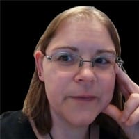 B2B Web Design Agency 49 Close-up portrait of a woman with glasses and light brown hair, resting her finger against her cheek against a dark background