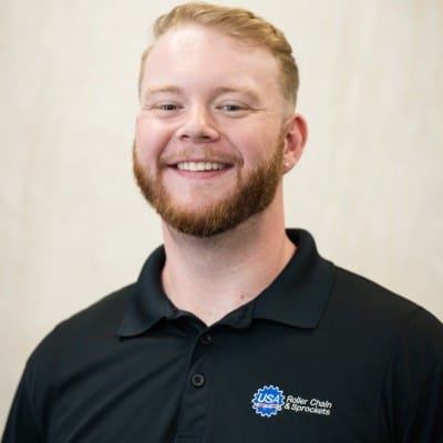 Home Page - NEW 247 Smiling man with short blond hair and a beard wearing a black polo shirt with a logo, photographed against a light neutral background