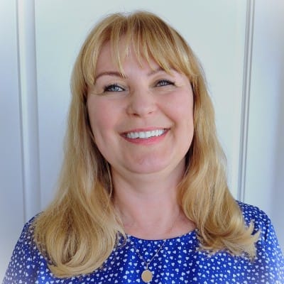 SaaS Marketing 42 Smiling woman with blonde hair wearing a blue patterned top, photographed against a light-colored background