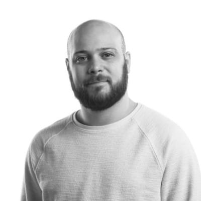 Home Page - NEW 247 Black-and-white portrait of a bearded man in a light crewneck sweater against a plain white background